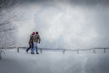 a couple walking through the snow on a cold icy winters day