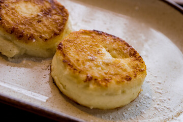 Cheesecakes sprinkled with sugar on a plate on a wooden table
