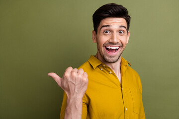 Profile portrait of impressed young man indicate thumb finger empty space proposition isolated on khaki color background