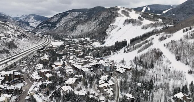 Flying backwards above famous Colorado ski resort town of Vail in winter, buildings and slopes covered in snow