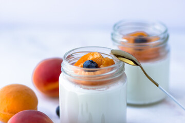 Homemade yogurt with apricot and blueberries. View from above, on a white background