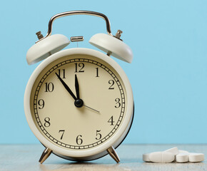 Round alarm clock and white oval tablets