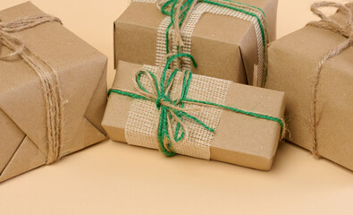 The box is packed in brown craft paper and tied with a rope on a beige background, gift