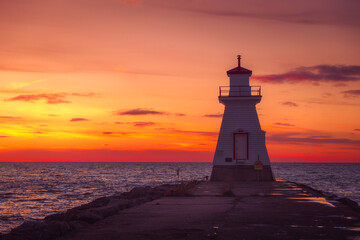 Lighthouse at sunset overlooking a lake.