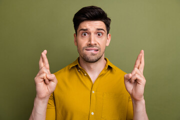 Portrait of nervous corporate person biting lips crossed fingers pray hope isolated on khaki color...