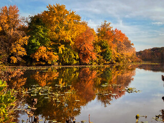 Autumn landscape with lake, trees and cloudy sky reflected in water.  View of the Brainerd Lake in...