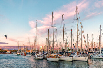 Yachts moored in the Mediterranean Sea near the Port Vell promenade in Barcelona at sunset, Spain....