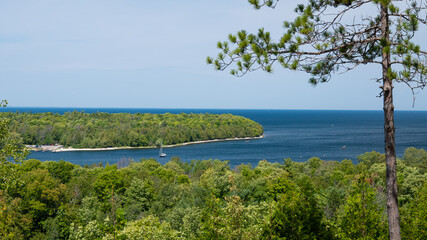 Scenic overlook view of the Green Bay of Lake Michigan in Door County, Wisconsin, with green vegetation, a cove with boats, and the blue water and sky.