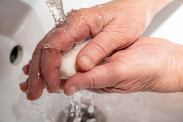 Fototapeta premium An elderly man washes his hands with soap, wrinkles, old.