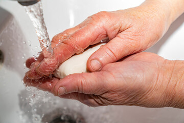 An elderly man washes his hands with soap, wrinkles, old.