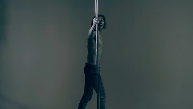 Pole dancer. Guy does gymnastic exercises on pole dance. Pole dancing for slim fitness body. Flexibility. Pole dance. Pylon dancing strength, flexibility, and grace. Strip muscular man dancer.