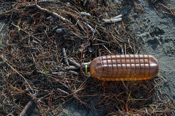 Beach in northern Italy after a violent storm. Plastic and cans returned from the sea together with algae. Pollution and waste on the beach. Marine pollution from plastic.