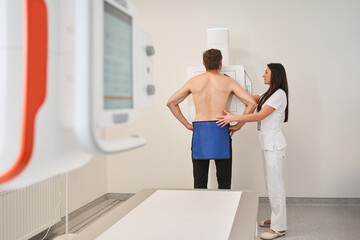 Woman doctor in medical gown helping patient at the x-ray machine