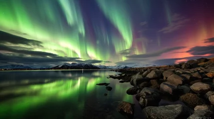 Fototapeten  a green and purple aurora bore over a body of water with rocks in the foreground and mountains in the background. © Olga
