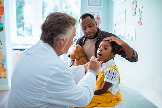 Pediatrician doing mouth Swab DNA Test to little girl at clinic