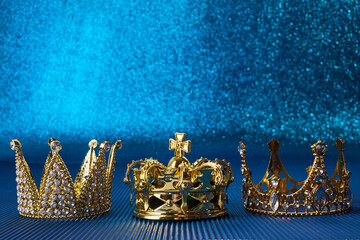 Epiphany Day or Dia de Reyes Magos concept. Three gold crowns on blue sparkling background