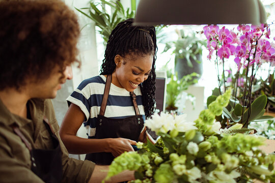 Two young florists making beautiful bouquet of flowers in shop