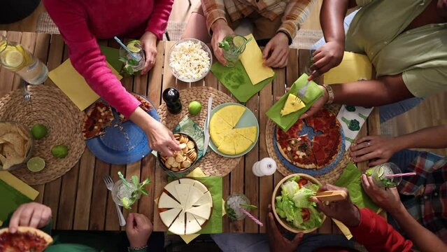 Family or friends celebrating. having pizza for dinner. Shot of people hands on a rustic wooden table with various types of food, top view.