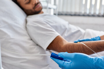 focus on hand of african american nurse setting drop counter with indian male patient on backdrop
