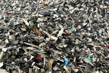 Obraz premium Shredded plastic pieces prepare for recycling. Raw cables material for reproduction. Sorting garbage on waste plant. Pile of scrap bottles on trash storage factory. Environmental concept