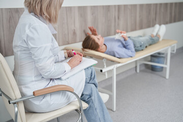 Psychotherapist writing notes, assessing patient's health and giving diagnosis to a woman