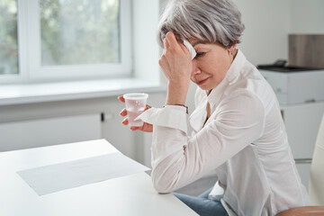 Crying woman holding glass of water and complaining about her problems