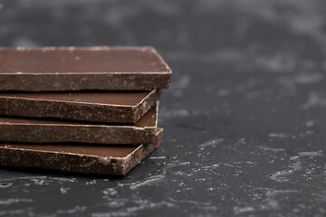 Dark chocolate on a dark background. Bar of dark chocolate. Chocolate pieces