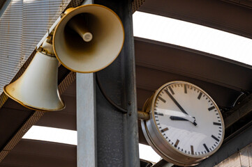Clock and loudspeaker on railway or bus station.