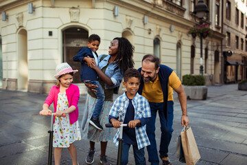 Happy multiracial couple with adorable little mixed raced children walking in the city