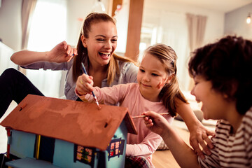 Young family painting a doll house at home