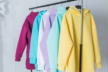Sweatshirts on hangers in the clothing store for sale. Row of colorful cashmere hoodies for youth. Multi-colored sweatshirts in a clothes stand in the mall.fashion woman's sweats hoodie