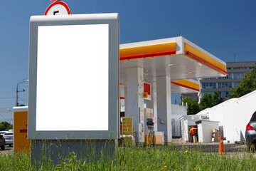Billboard next to a gas station on a green lawn. Mock-up.