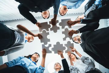 Multiethnic business people holding jigsaw pieces and merge them together as effective solution solving teamwork, shared vision and common goal combining diverse talent. Below view. Habiliment