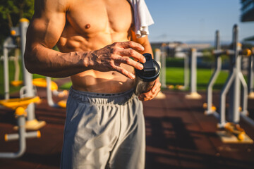 One caucasian man young male athlete take a brake during outdoor training in the park outdoor gym hold supplement shaker in hand happy confident strong copy space - Powered by Adobe