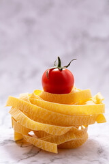 Nest of pasta tagliatelle and tomato placed on top