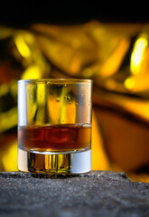 glass of whiskey with golden background 