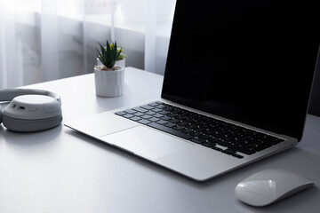 Laptop computer keyboard mouse and music earphones on a white table background