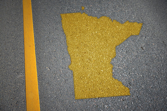 yellow map of minnesota state on asphalt road near yellow line.