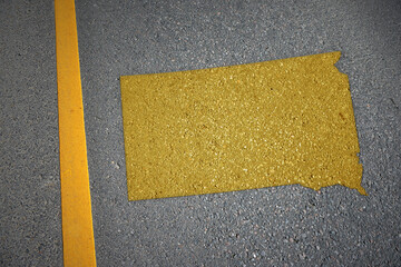 yellow map of south dakota state on asphalt road near yellow line.