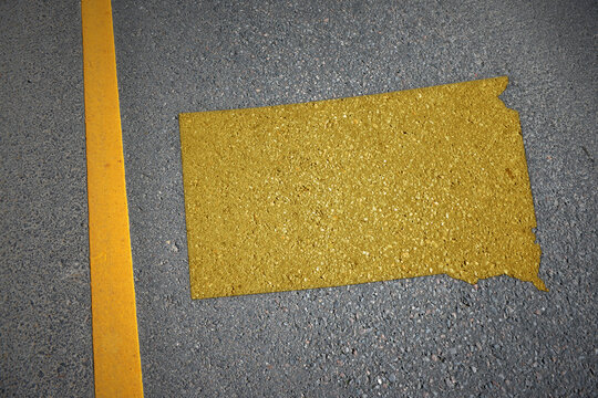 yellow map of south dakota state on asphalt road near yellow line.