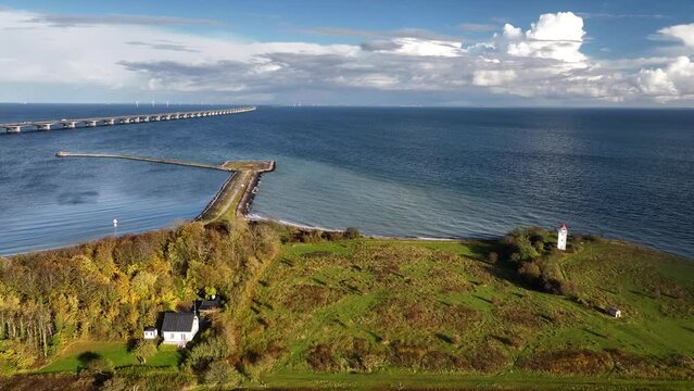 Aerial footage of Denmark's coastline with the Storeb&aelig;lt Bridge spanning across the horizon, connecting two coasts and Knudshoved Lighthouse. Knudshoved Lighthouse against the backdrop of the vast sea