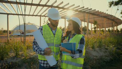 Two Caucasian professional engineers constructor man holding scheme plan woman controller check...