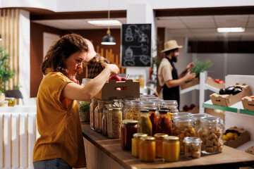 Healthy living woman in zero waste shop looking to buy freshly handpicked apples and other fruits. Customer shopping for chemicals free groceries in local neighborhood store