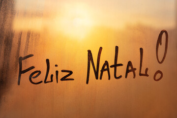 Congratulation lettering Portuguese Feliz i\Natal is Merry Christmas in english on muddy wet orange...
