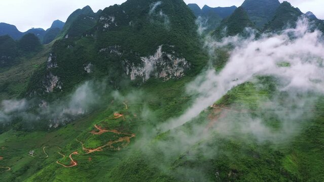 Drone of green mountains, road and nature for travel, adventure or holiday with background for eco tourism. Aerial view of landscape, clouds and highway infrastructure in Vietnam, Ma Pi Leng Pass