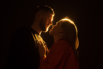 A silhouette of a loving couple about to kiss, surrounded by a warm golden halo of light, creating...