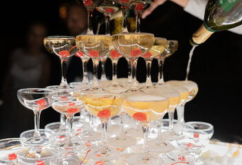 Champagne glasses standing in a tower at the wedding party. Champagne glass pyramid. Pyramid of glasses of wine, champagne, tower of champagne. Wedding party at night