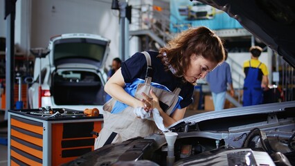 Mechanic in repair shop using torque wrench to tighten screws after opening car to check its...