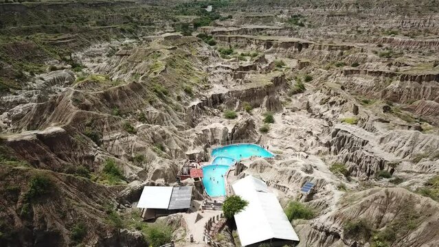 Aerial drone footage of the Piscina natural mineral in the Tatacoa desert in Colombia, South America. Grey desert. Arid gray and green canyon. Flying over desert. High quality 4k footage.