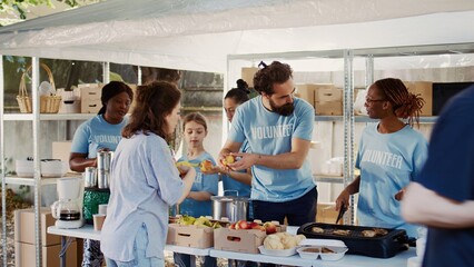 Voluntary individuals in blue t-shirts serving free, freshly prepared food and provisions to the...